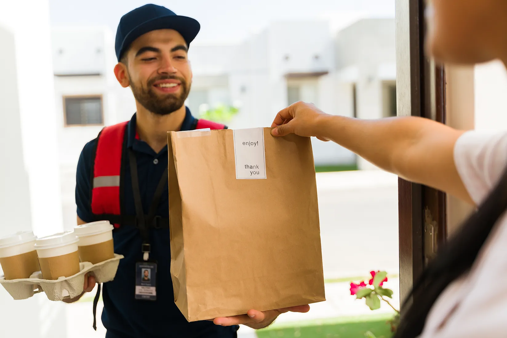 delivery driver carrying brown bag and takeaway cups